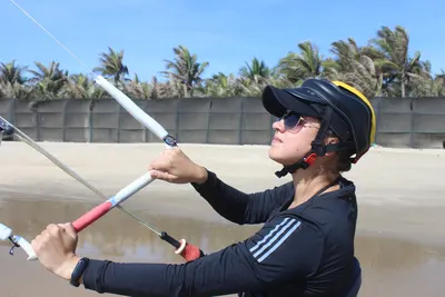 K1 student flying a kite in helmet and harness, Malibu beach, Mui Ne