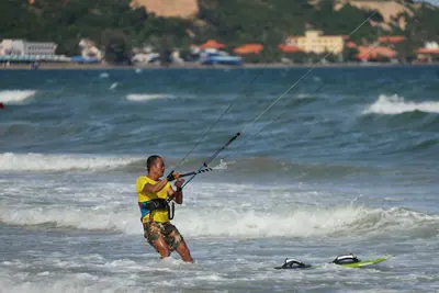 A rider walking out of the water with the kite, Mui Ne coast behind