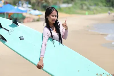 Happy student with her surfboard after a lesson in Mui Ne