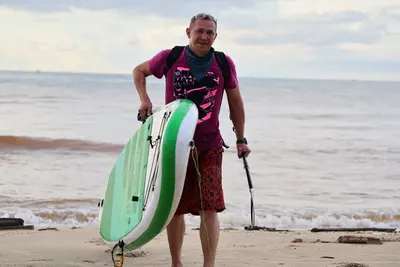 K1 guest carrying a SUP board up the beach