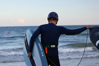 Heading into the water with a wing and a foil board